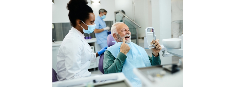 Doctor watches as her patient admires his new smile while sitting in the operatory. 